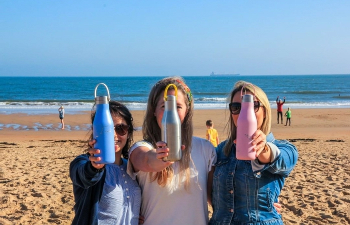 Women holding Ohelo environmental sustainable bottles on sunny beach