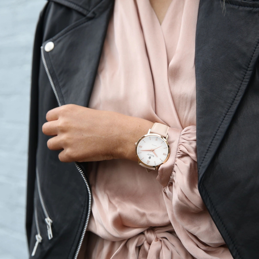 Person wearing luxury pink Montre Parfaite watch with white face