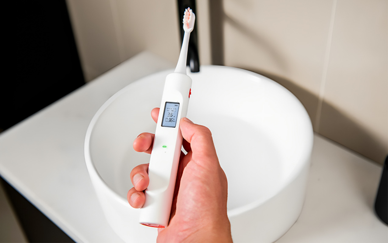 Close up of digital panel of the toothbrush breathalyser concept being held by a person over a sink