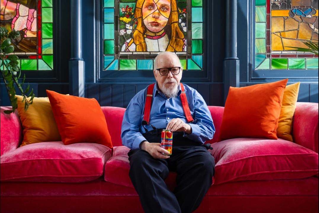 Sir Peter Blake sits on colourful sofa with Budweiser can. Image courtesy of www.budweiser.co.uk